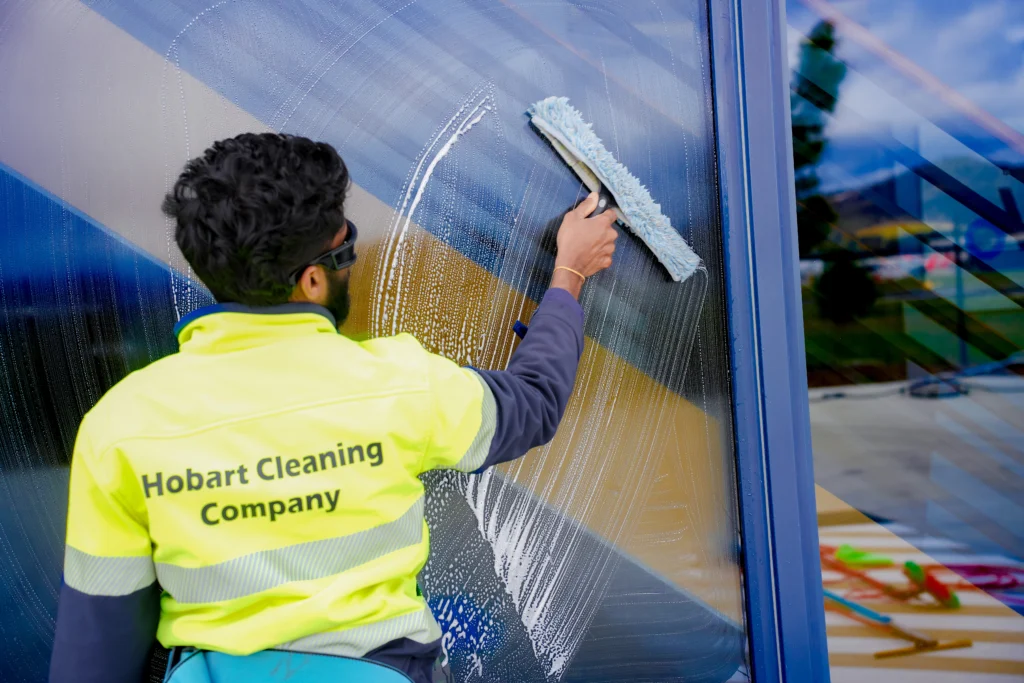 An employee of Hobart Cleaning Company washing exterior glass panels, demonstrating professional commercial window cleaning services in Hobart.